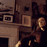 a woman is sitting in a chair in front of a fireplace in a living room