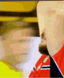 a close up of a man 's face with a beard and a red shirt .