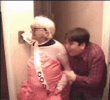 a man is helping an elderly woman in a pink dress .