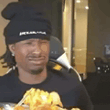 a man wearing a chef 's hat is sitting at a table with a plate of food .