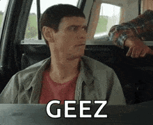 a man is sitting in the back seat of a car with the word geez written on the screen .