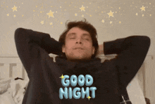 a man laying on a bed with his eyes closed and a good night sticker on his shirt