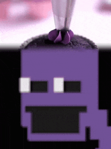 a purple pixelated face is being decorated with purple frosting by a piping bag