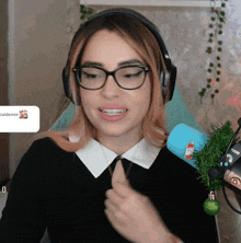 a woman wearing glasses and headphones is smiling in front of a microphone with a sticker on it that says cuidense