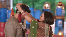 a woman is putting a garland around a man 's neck .