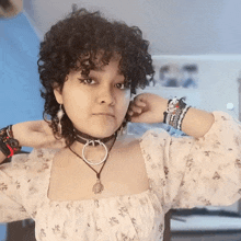 a woman with curly hair is wearing a choker necklace and bracelets