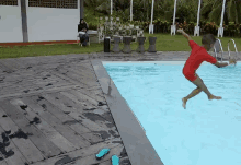 a young boy in a red shirt jumps into a swimming pool