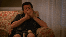 a man is sitting in a chair with a floral pattern on it
