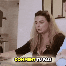 a woman sitting at a table with the words comment tu fais on the bottom right