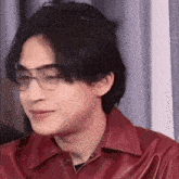 a man wearing glasses and a red shirt is making a face .