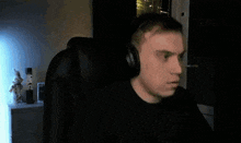 a man wearing headphones looks surprised while sitting in front of a computer screen