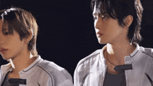 two young men are standing next to each other in a dark room looking at the camera