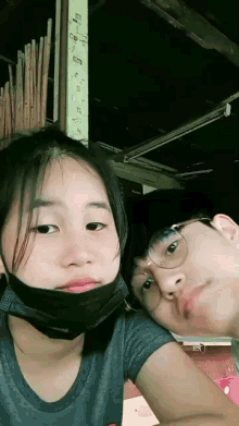 a girl wearing a mask and a boy wearing glasses are posing for a picture