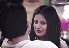 a woman looks at a man in a white shirt with the words mcreations on the bottom right