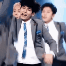 a man in a suit and tie is dancing on a stage with other men .