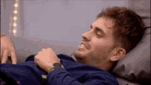a man is laying on a bed with a watch on his wrist and smiling .
