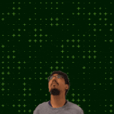 a man stands in front of a green background with the number 3 + 4 written on it