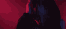 a close up of a person 's face with dreadlocks in a dark room with red lights .