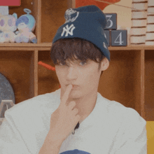 a young man wearing a ny hat and a white shirt