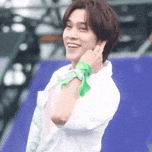 a man wearing a white shirt and a green scarf around his neck is smiling .