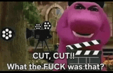 a purple dinosaur is holding a clapper board in front of a movie camera .