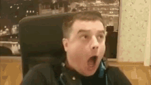 a man wearing headphones is sitting in a chair and making a surprised face .