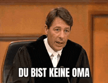 a man in a judge 's robe says du bist keine oma in front of a microphone .