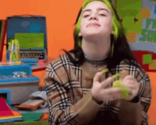 billie eilish is wearing a plaid shirt and green hair while playing with a toy .