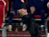a man in a suit is standing in front of a row of red seats and covering his face with his hands .