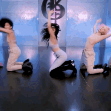 a group of women are kneeling on the floor in front of a wall with a dollar sign