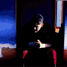 a man in boxing gloves is sitting in a dark room with a window