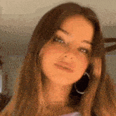 a close up of a woman wearing hoop earrings and a purple shirt .