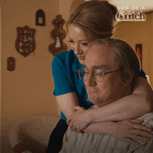 a woman is hugging an older man with the words son of a catch behind them