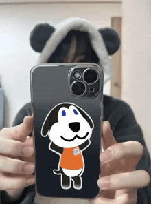 a person wearing a panda hat is holding up a phone with a dog on it