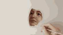 a person is painting a woman 's face with a brush and the words made in animotica are visible
