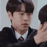 a man in a suit and tie is being touched by another man 's hand .