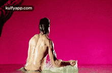 a man without a shirt is sitting in a pool of water .