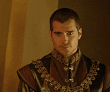 a man in a costume with a gold chain around his neck is looking at the camera