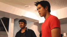 a man in a red shirt is standing next to another man in a black shirt