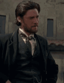 a man with a beard is wearing a suit and tie .