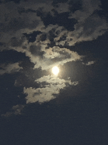 a full moon is surrounded by clouds in a dark sky