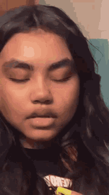 a close up of a girl 's face with her eyes closed and a black shirt on .