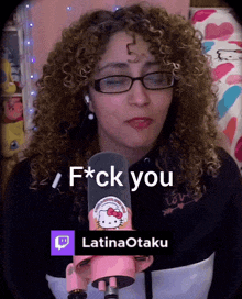 a woman with curly hair and glasses says f * ck you in front of a hello kitty microphone