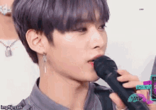 a young man with purple hair is holding a microphone in his mouth .