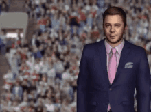 a man in a suit and pink tie stands in front of a crowd