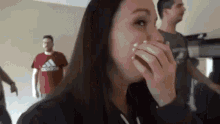 a woman is covering her mouth with her hand while a man stands behind her .