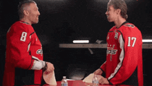 a man in a red jersey with the number 8 on it is shaking hands with another man in a red jersey with the number 17 on it