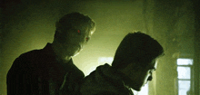 a man with red eyes stands next to another man in a dark room