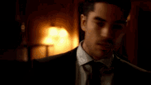a man in a suit and tie is standing in a dark room looking at the camera .