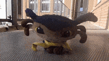 a stuffed animal with a yellow scarf around its neck is standing in front of a building